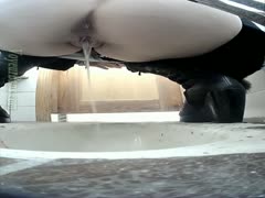 On a webcam, a white black cock slut wearing black leather boots urinates in the restroom.